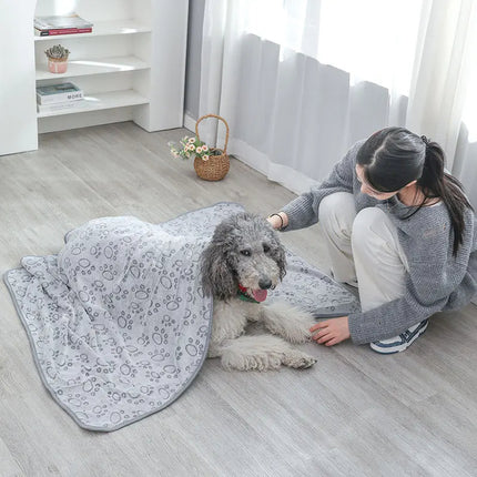 Large curly dog snuggled under gray dog blanket